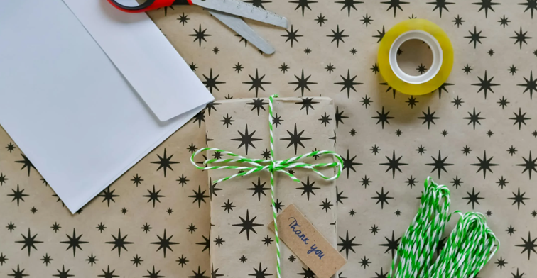 Creatief ingepakt cadeau met zwart sterpatroon, groen-wit touw en label met 'thank you'.
