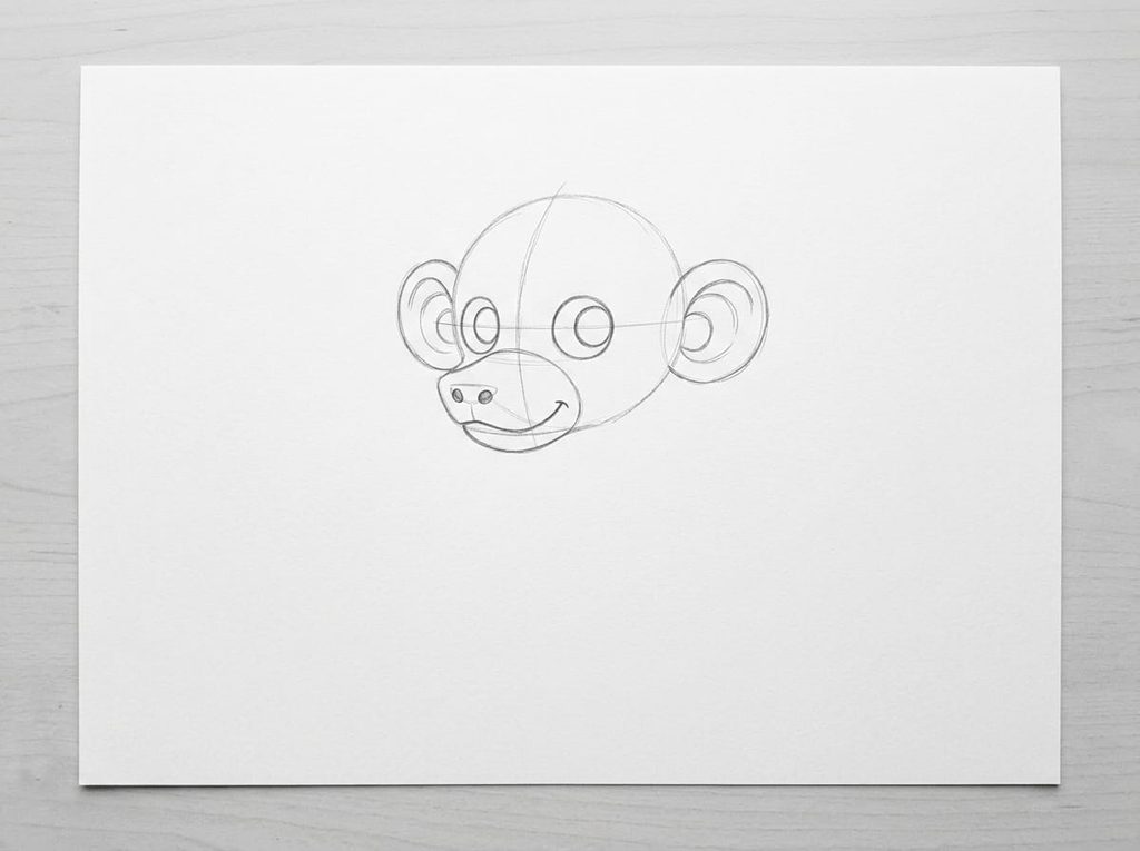 Op een vel wit papier ligt op een houten tafelblad een gedetailleerdere schets in grafietpotlood. De schets toont een hoofd met grote, ronde ogen, twee kleine, ronde neusgaten en een brede, gebogen mond op de snuitvorm. Aan weerszijden van het hoofd zijn twee grote, ronde oren getekend. De schets is gemaakt met dunne, lichte lijnen.